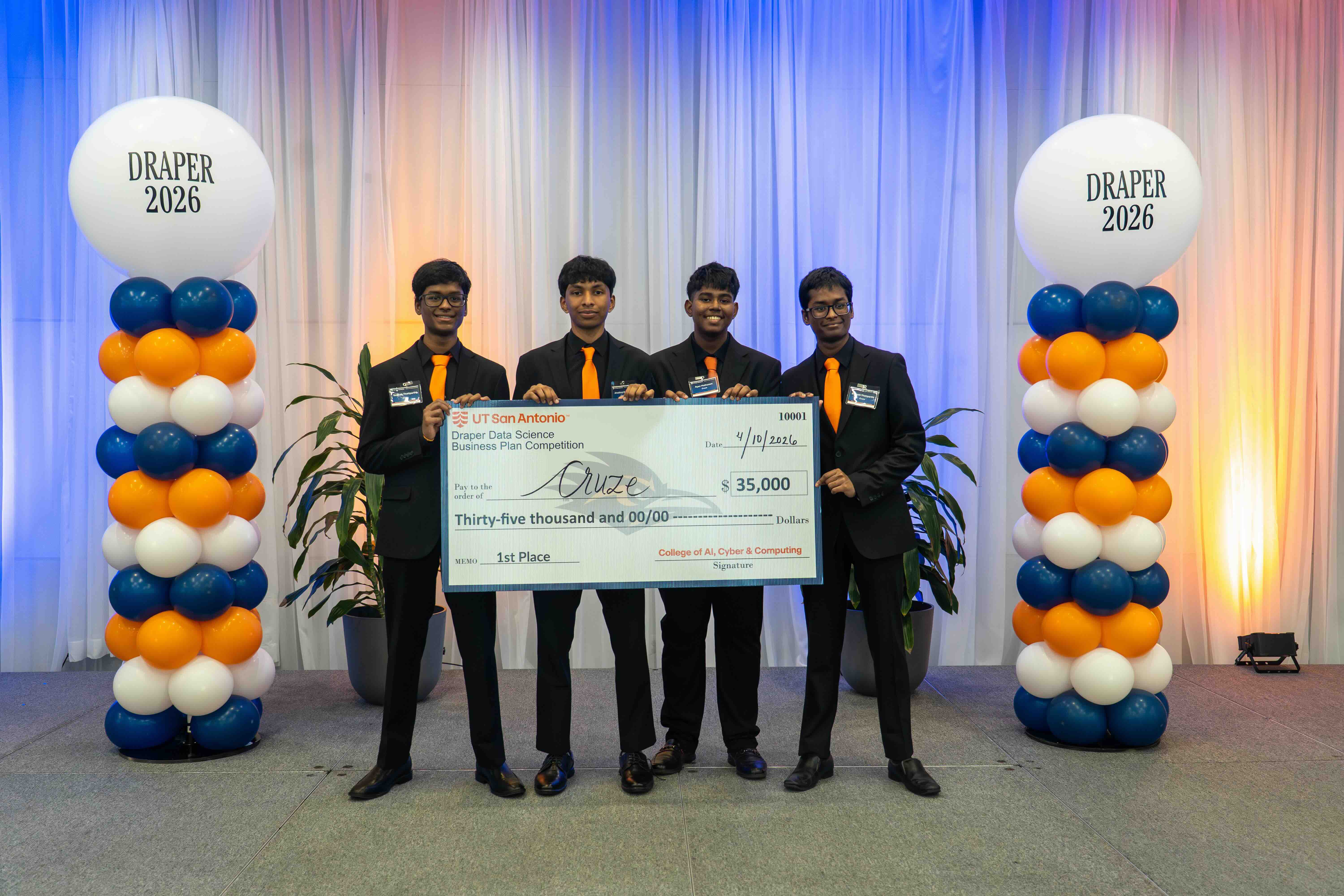 Students win first place in the Draper Competition. Students are holding a check.