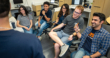 Computer Science students sitting in a research lab during a discussion.