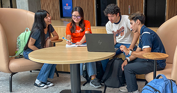 Four students sitting at a table appear to be studying.